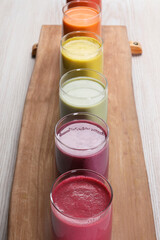Board with many different tasty smoothies on white wooden table