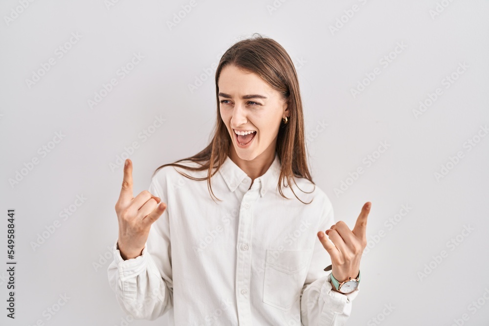 Poster young caucasian woman standing over isolated background shouting with crazy expression doing rock sy