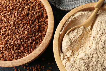 Buckwheat flour and grains in bowls on black table, top view
