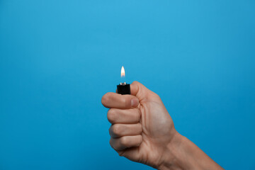 Woman holding lighter on light blue background, closeup. Space for text - obrazy, fototapety, plakaty