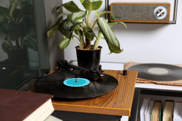 Stylish turntable with vinyl disc on table in room