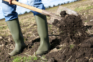 Man digging soil with shovel in field, closeup