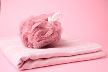 Shower puff with towel on pink background
