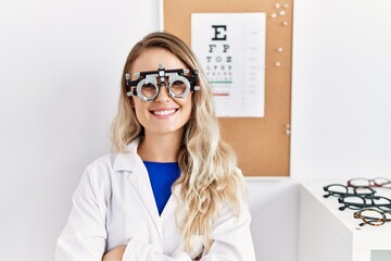 Young beautiful optician woman wearing optometry glasses at the clinic happy face smiling with...