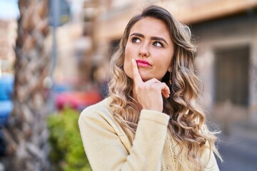 Young woman standing with doubt expression at street