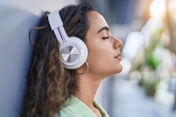 Young beautiful hispanic woman listening to music at street