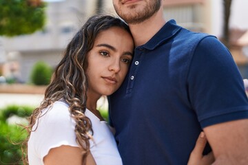 Obraz premium Young hispanic couple hugging each other standing with relaxed expression at park