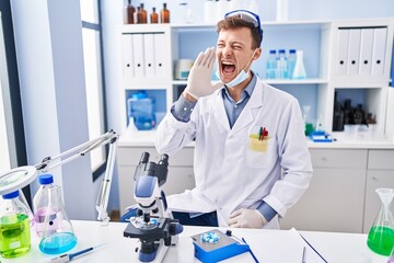 Caucasian man working at scientist laboratory clueless and confused with open arms, no idea and doubtful face.