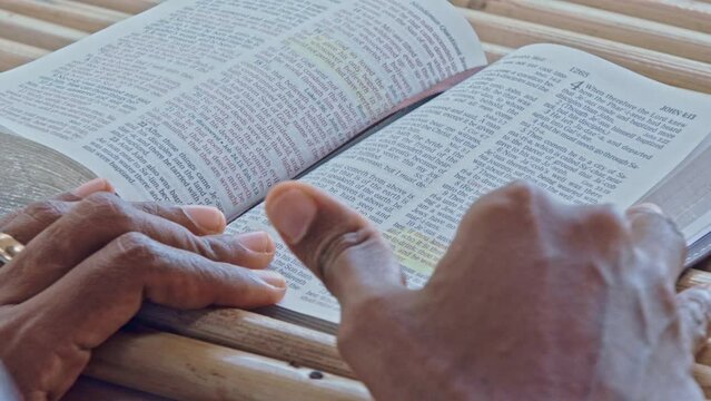 A person's fingers skims over verses on a Bible page.