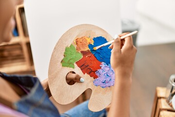Young african american woman smiling confident mixing color on palette at art studio