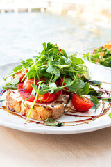 Tasty savory tomatoes on slices of toasted and young green sprouts of peas garnished on wooden table in a café with view on beach at day sun light on background.