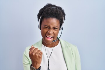 African american woman wearing call center agent headset very happy and excited doing winner...
