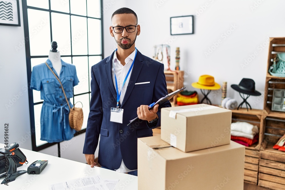 Poster African american man working as manager at retail boutique puffing cheeks with funny face. mouth inflated with air, crazy expression.