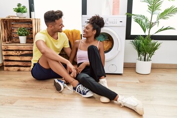 Man and woman couple hugging each other waiting for washing machine at laundry room
