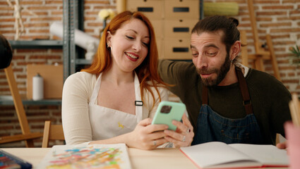 Man and woman couple using smartphone and drawing at art studio