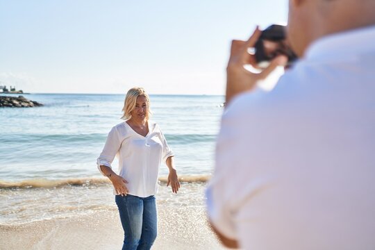 Middle age man and woman couple making photo using camera at seaside
