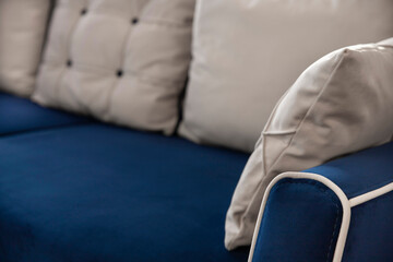 Blue upholstered furniture made of velor fleece fabric and white quilted pillows in a blurred...