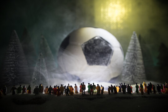 World cup at wintertime concept. Football (Soccer) ball on snowy decorated table with toy miniatures. New Year Christmas theme. Selective focus.