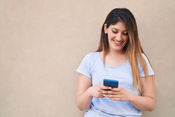Young hispanic woman smiling confident using smartphone over isolated white background