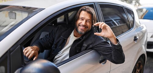 Middle age man smiling confident holding key of new car at street