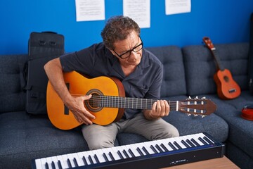 Middle age man musician playing classical guitar at music studio