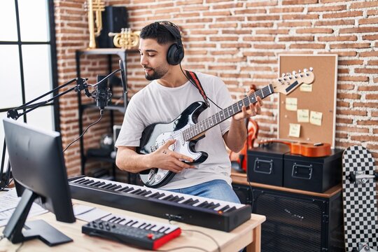 Young arab man artist singing song playing electrical guitar at music studio