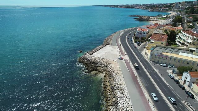 Aerial view overlooking the marginal promenade, in sunny Caxias, Portugal - reverse, drone shot