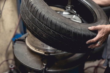A man removing a tire from the rim after using a tire bead breaker at a vulcanizing shop.
