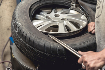 A man using a steel rod to assist in removing a tire from the rim. Using a tire bead breaker at a...