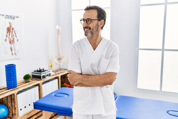 Middle age man with beard working at pain recovery clinic smiling looking to the side and staring away thinking.