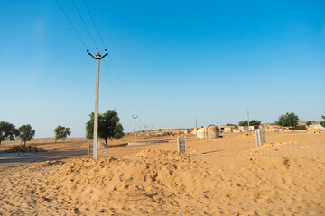 Ranautar, remote desert village inside the desert. Distant horizon, Hot summer with cloudless clear blue sky background, Thar desert, Rajasthan, India.