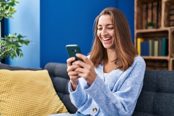 Young woman using smartphone sitting on sofa at home