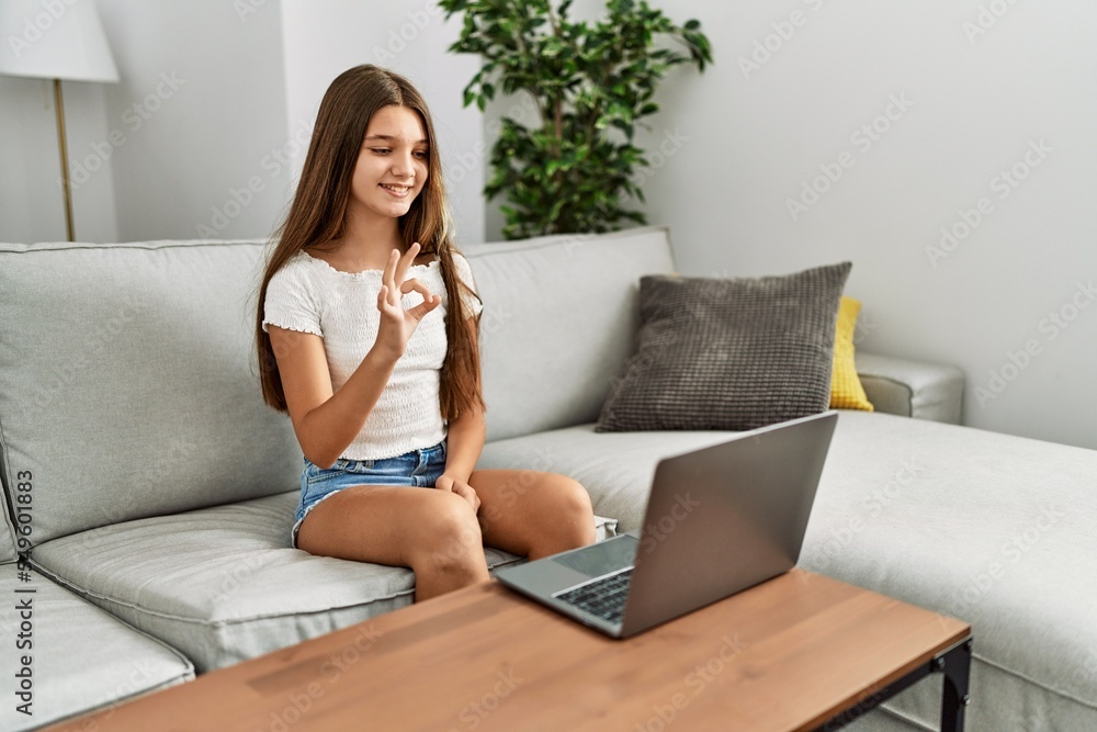 Sticker Adorable girl having video call communicating with deaf language sitting on sofa at home