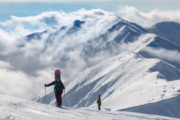 An active female climbs into snowy mountains against the background of a large massive Marmaros mountain range