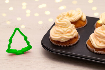 tray with freshly made cupcakes or maffins decorated with cream on wood table at the kitchen