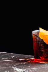 negroni cocktail glass aperitif detail on a marble table with a black background