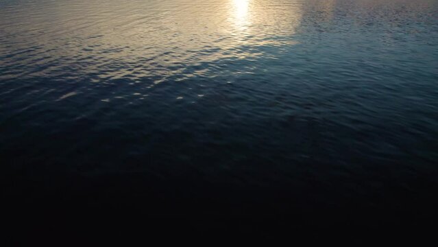 Cinematic drone tilt up dolly shot of a lake and mountains with sunset