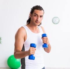 Young handsome man doing sport exercises indoors