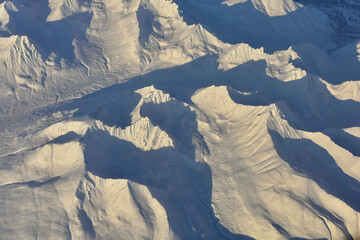 Aerial view of snowy Alaska Range mountain landscape.