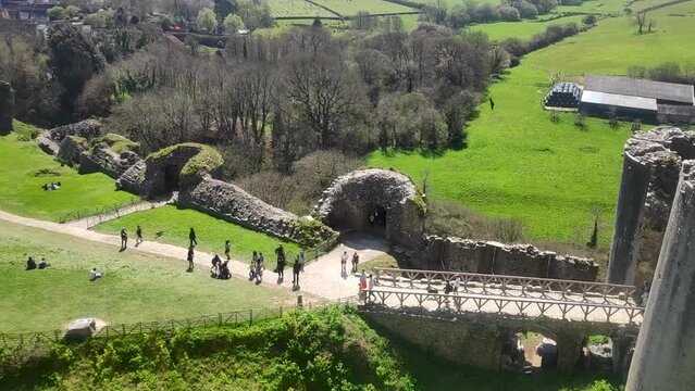 Slow pan of Cofre Castle, showing families and travelers enjoying the facility. A small town in the background is surrounded by countryside farmland. Filmed from the highest peak