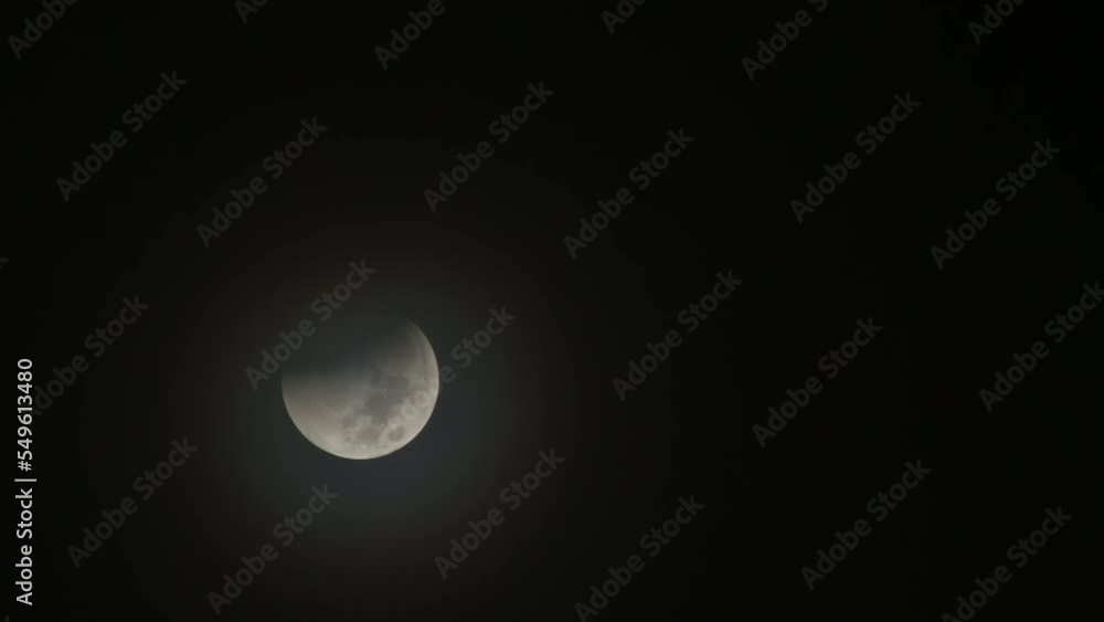 Poster partial lunar eclipse with shadow starting to appear and clouds rolling over it - 11-08-2022
