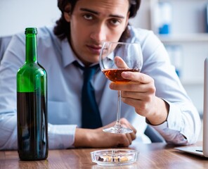 Male employee drinking alcohol and smoking cigarettes at workpla