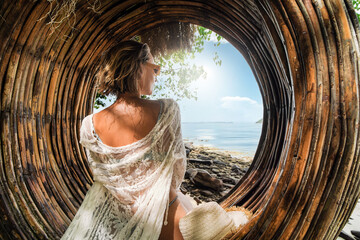 Back view of beautiful blonde woman relaxing on the amazing Coral Beach in Thailand, sitting on a...