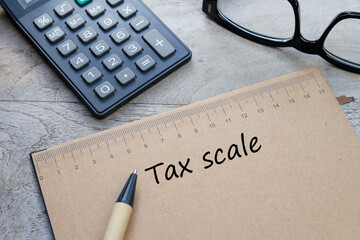 Tax Scale wordings below the scale with a pen, calculator, and eyeglasses