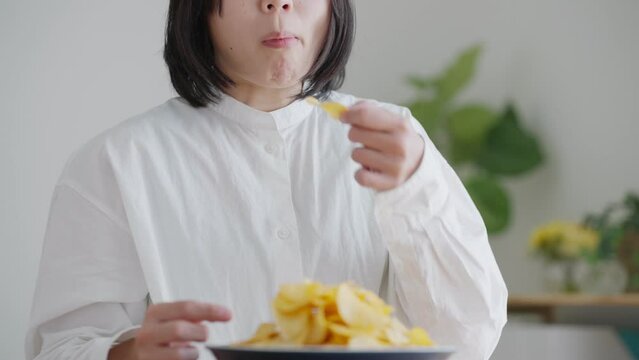 ポテトチップスを食べる女性（健康・ダイエット）