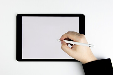 Top view of hand holding pen writing tablet computer with blank white screen. with copy and business design
