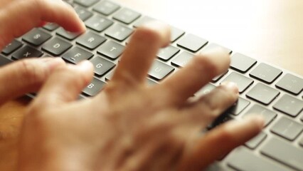 Asian hands randomly typing or clicking on portable wireless keyboard, working from home