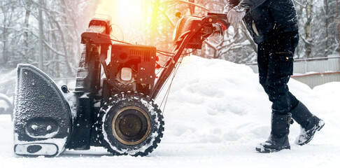 a janitor on a snowplow removes snow in the courtyard of a residential building
