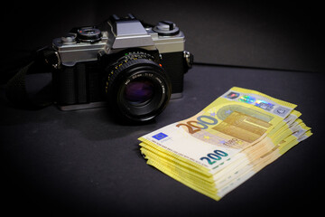 next to an reflex camera lies a stack of 200-Euro banknotes