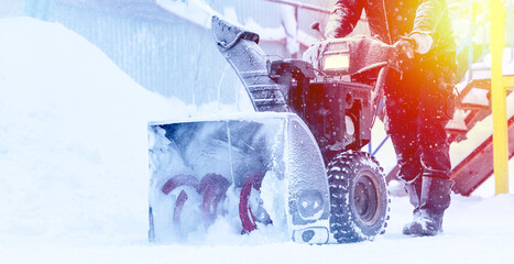 a janitor on a snowplow removes snow in the courtyard of a residential building